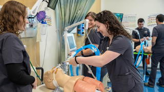 Three female Saint Joseph's nursing students in clinical classroom working on simulation patient