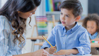 Stock image of teacher and young student in classroom