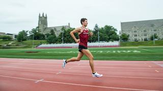Zach Michon running on the Saint Joseph's track with Barbelin Hall in the background