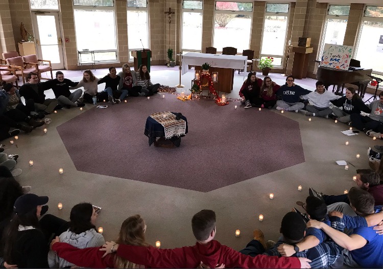 A group of worshippers huddled in a room around a circle of lit candles
