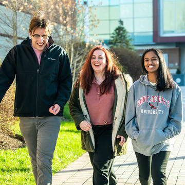 Three Saint Joseph's University students talking and laughing as they walk outside