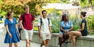 Five Saint Joseph's University students wearing summer outfits walking outside on campus