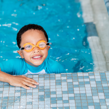 Young child smiles and learns to swim