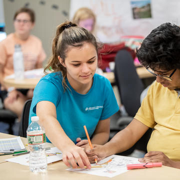 Teacher helping a younger teenage boy with his homework