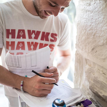 young man smiling while filling out a clipboard of paperwork