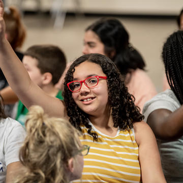 Young girl raises her hand