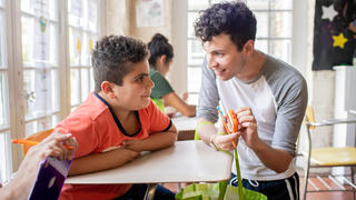young male showing a younger male teen some educational tools