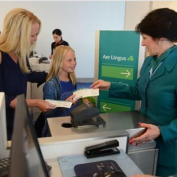 woman and young girl handing tickets to a flight attendant at an airport