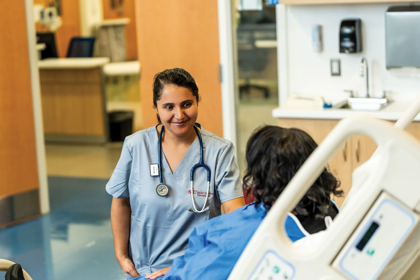 Saint Joseph's University nursing student in a patients room talking to the patient