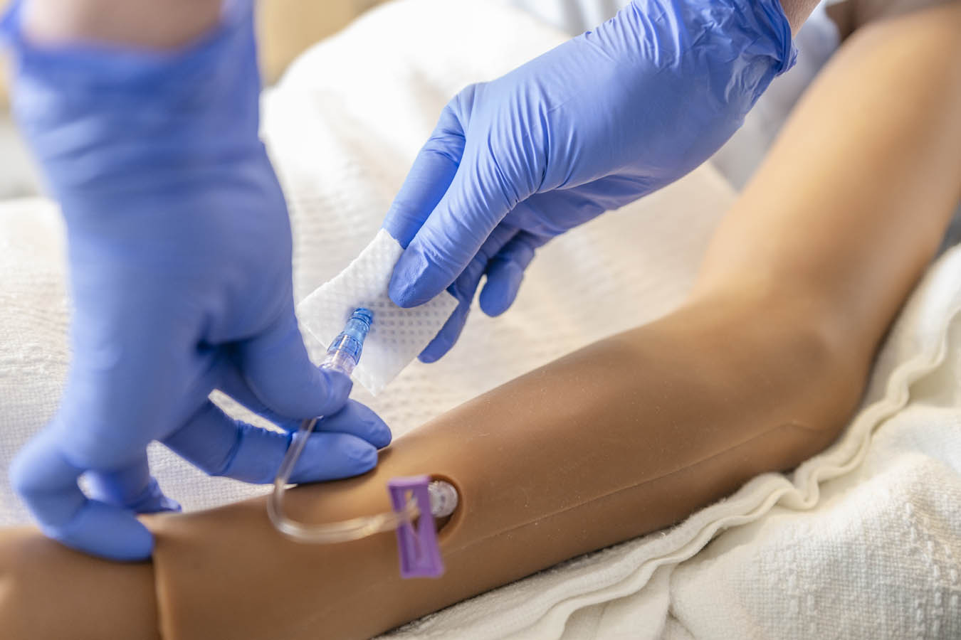 Saint Joseph's University patient simulator with students practicing IV is classroom settings