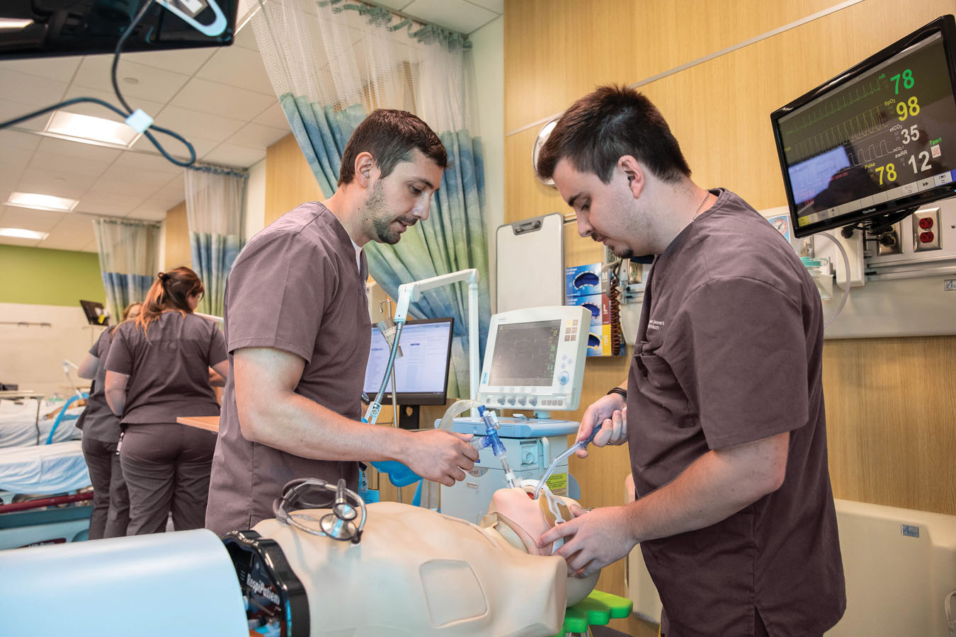 Two Saint Joseph's University students in the respitory care lab with a simulation patient