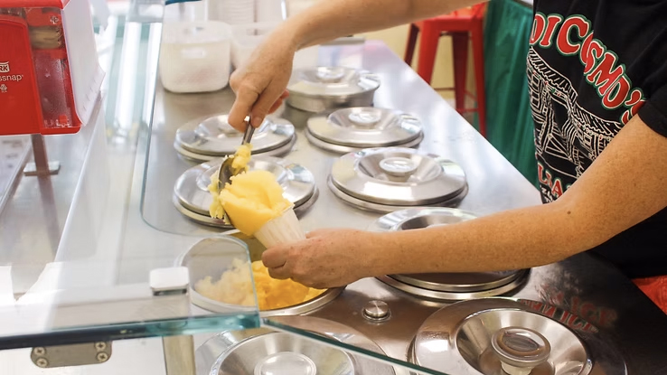 woman scooping lemon water ice into cup