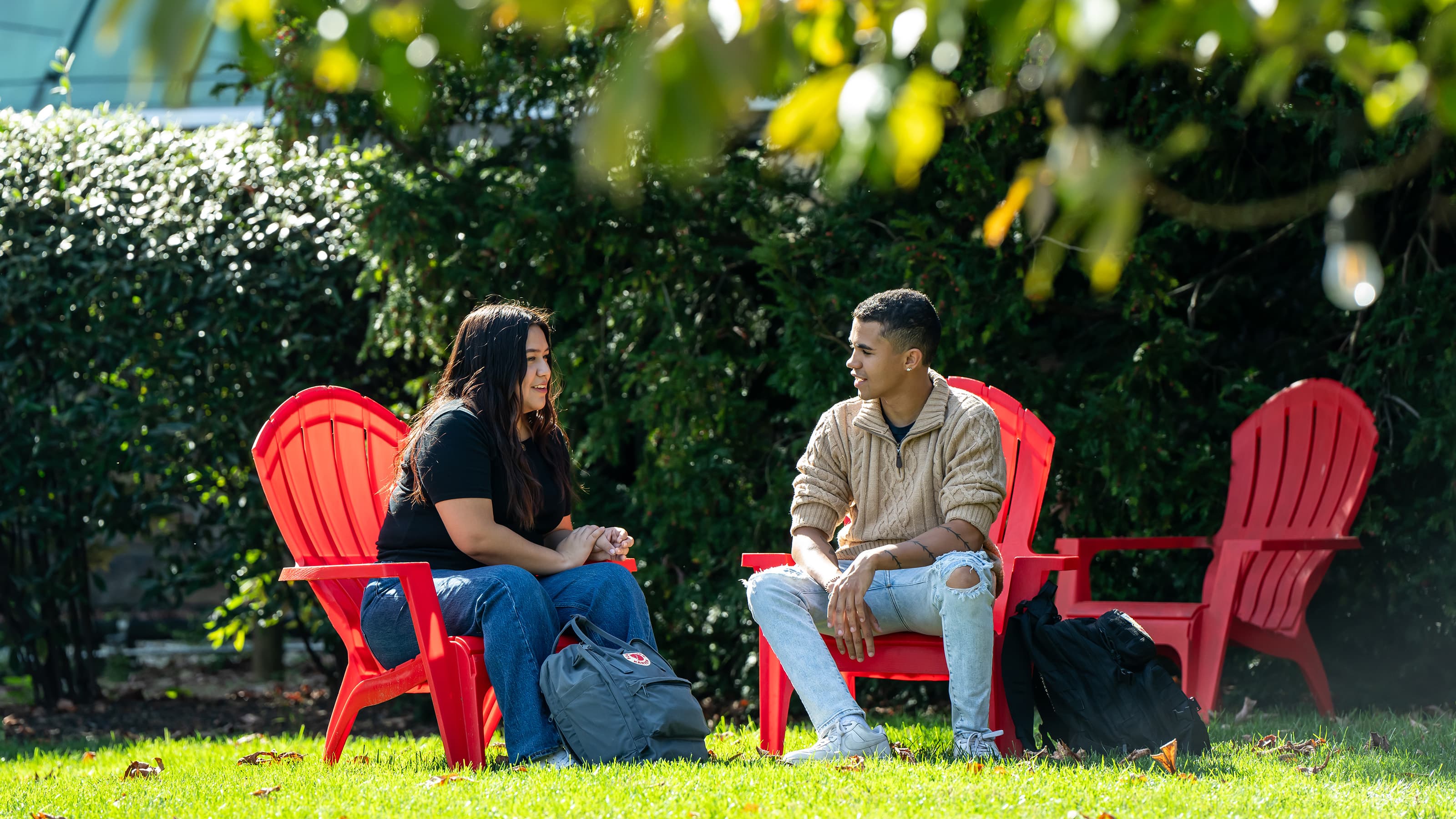 Two students sitting on adirondack chairs on Hawk Hill