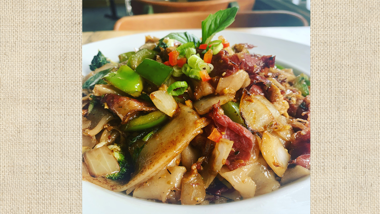 photo of pastrami drunken noodles on a beige background