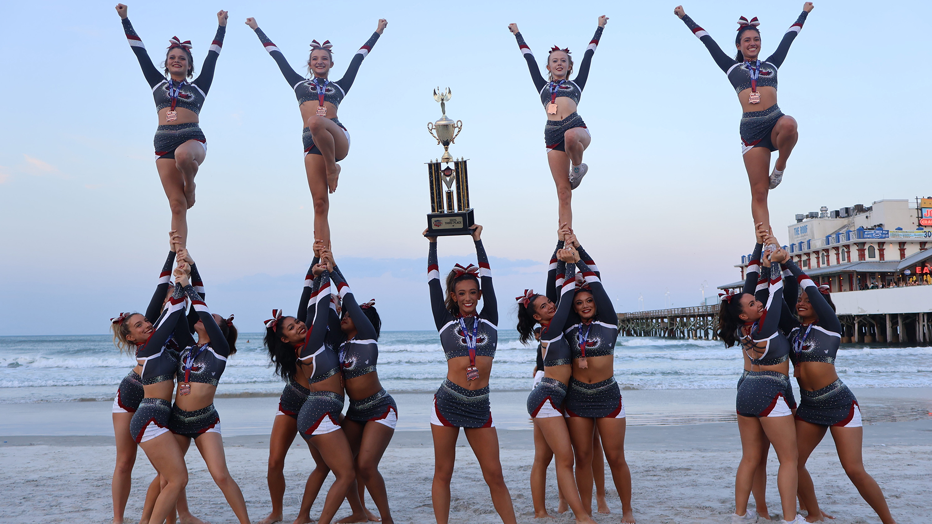 The cheer team holding up its trophy on the beach