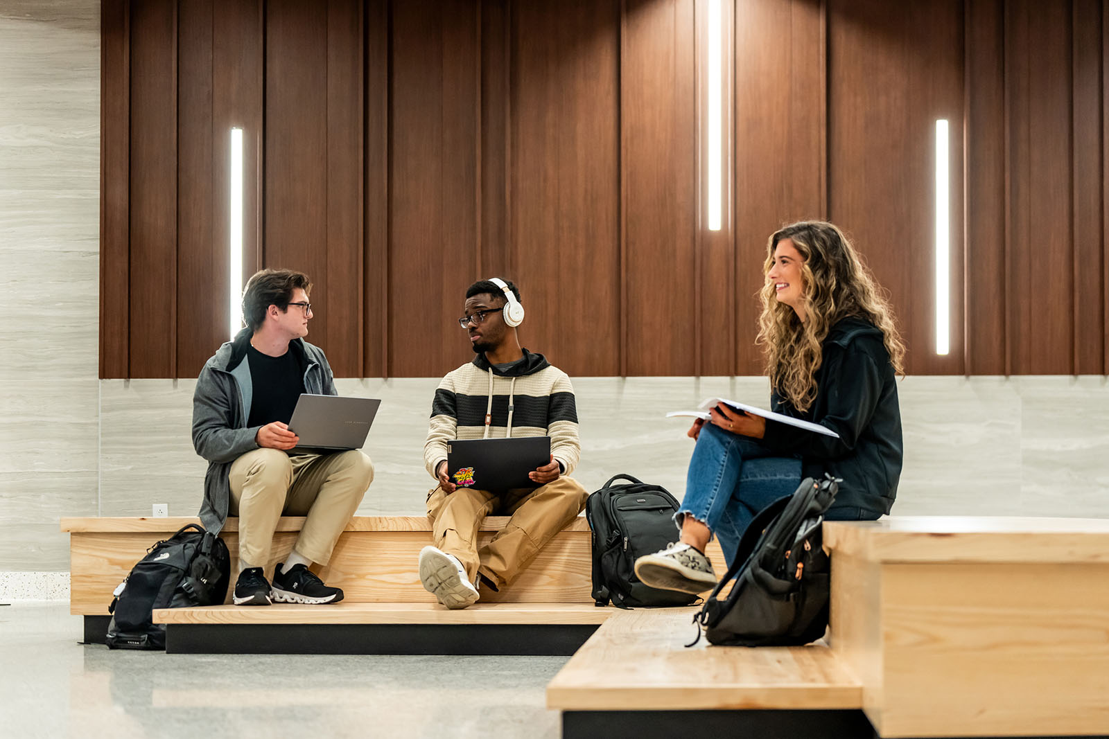 Three students sitting in a public study space working on computers
