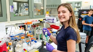 Abby Robinson, BS ’27, holding a test tube in a lab