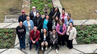 Students and faculty stand together in front of a fountain.