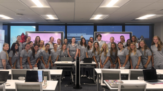 A group of smiling students in gray scrubs
