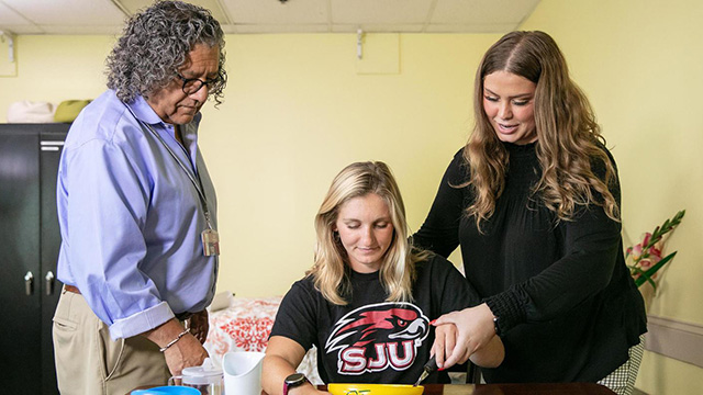 Two students and an occupational therapy teacher working on an exercise