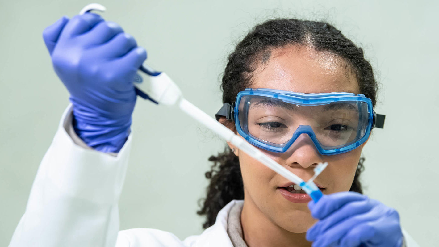 A woman in a white lab coat working with lab equipment