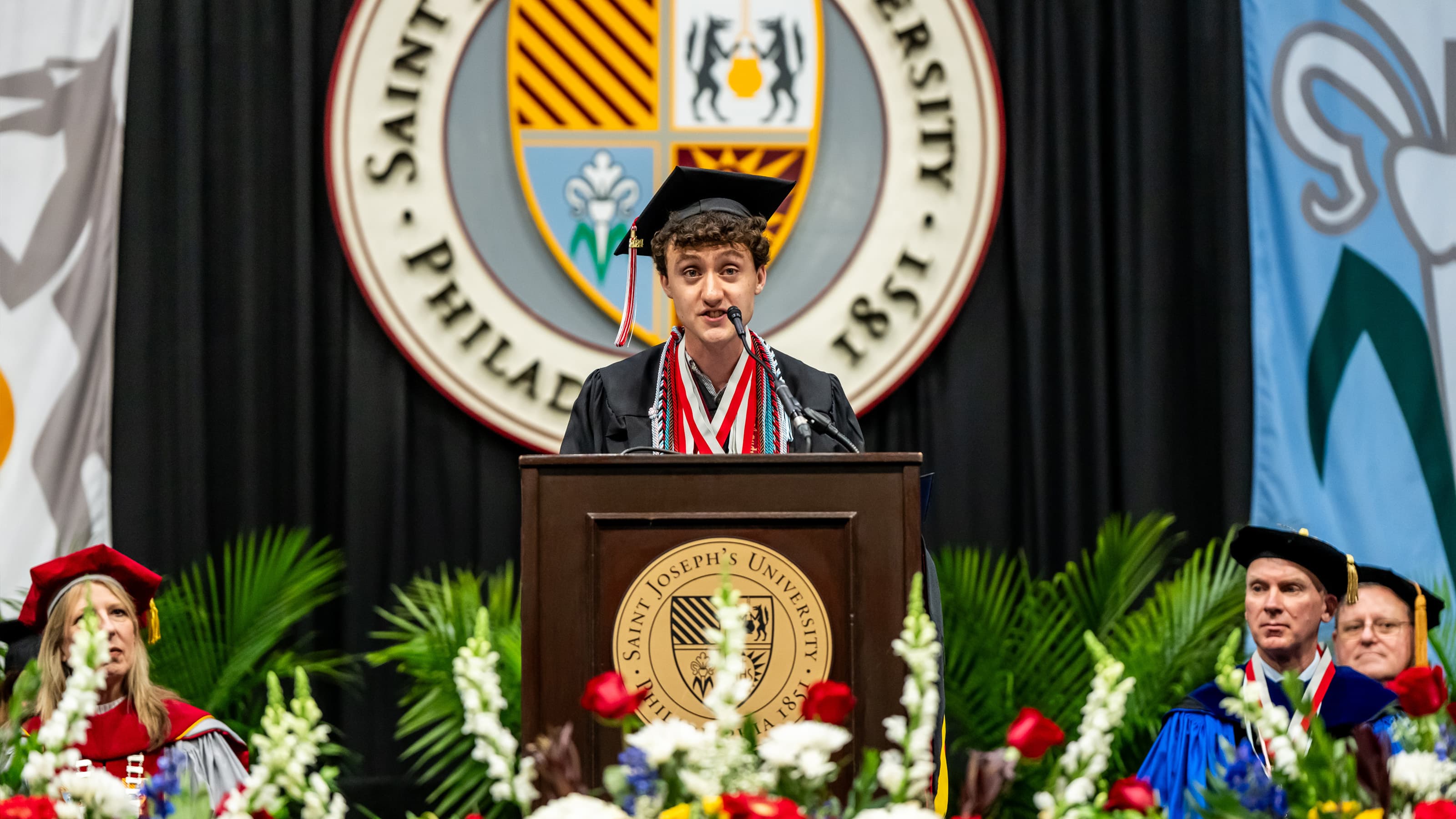 Student in regalia delivering valedictory address at Commencement