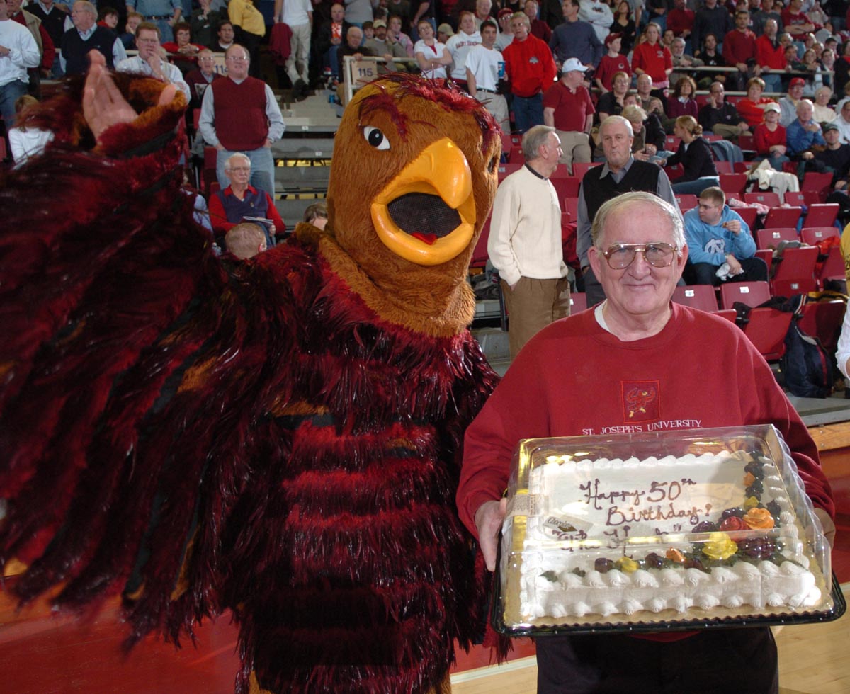 The Hawk mascot standing next to the original Hawk, Jim Brennan, holding a birthday cake