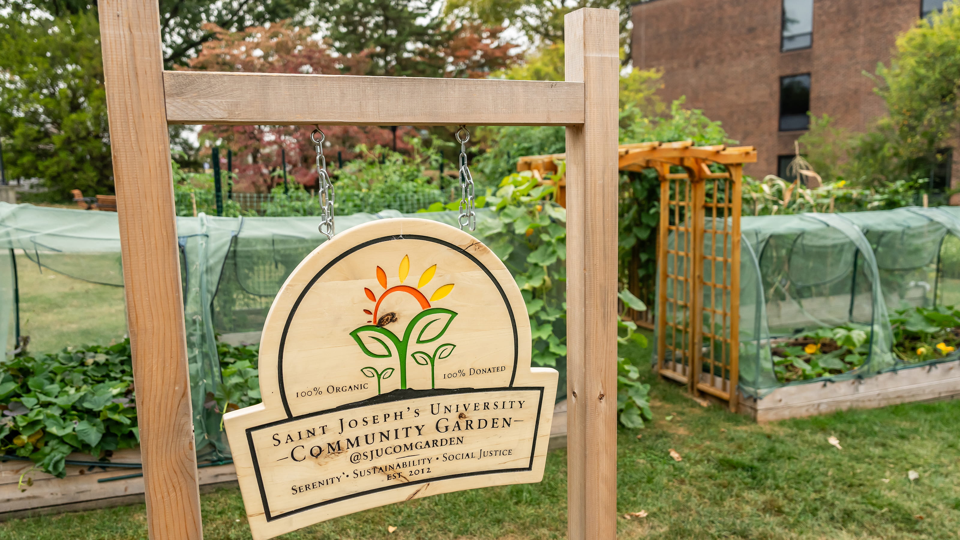 Saint Joseph's wooden community garden sign with the background of the plants