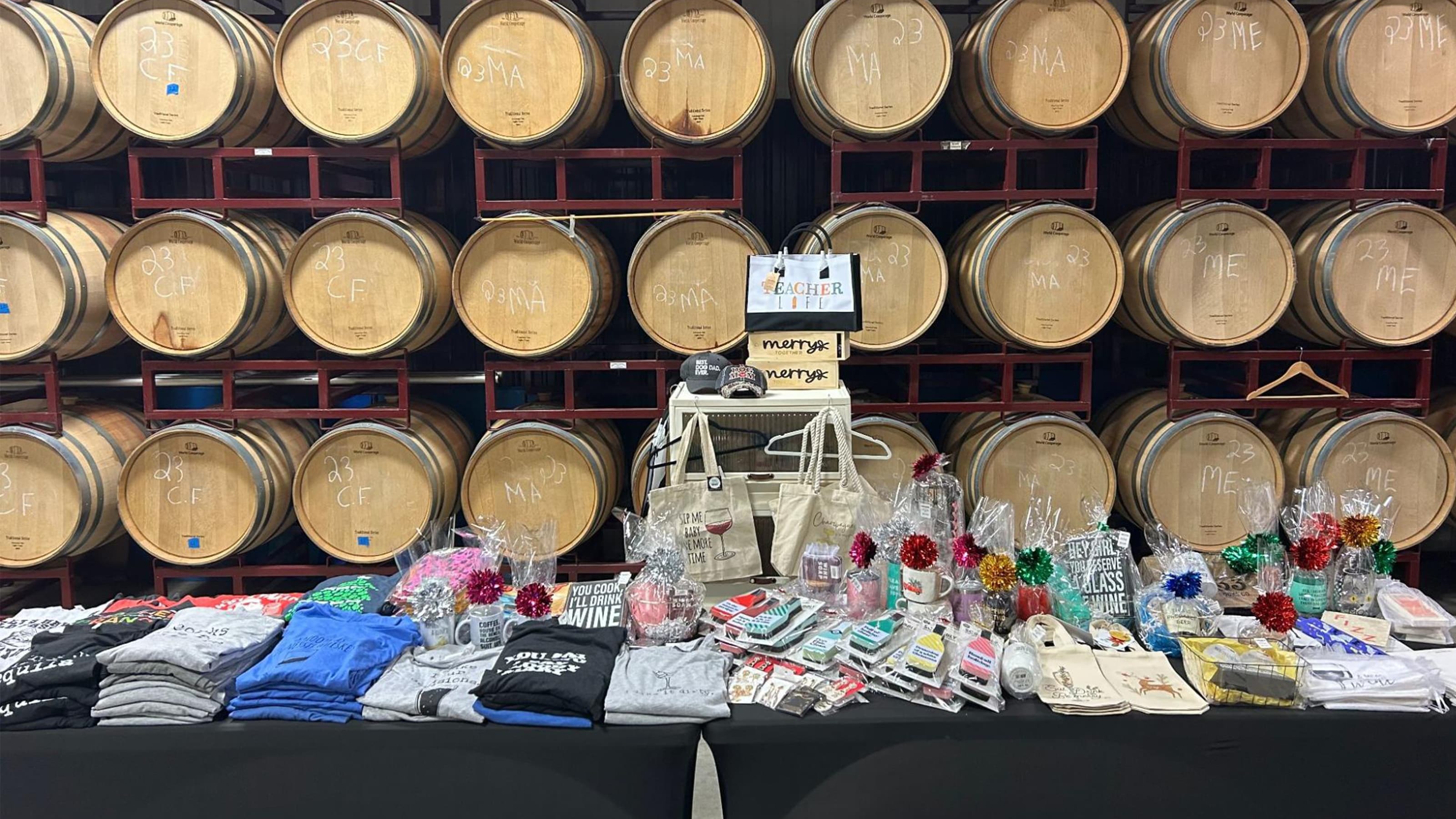 Wine barrels with wine-themed gifts on table.