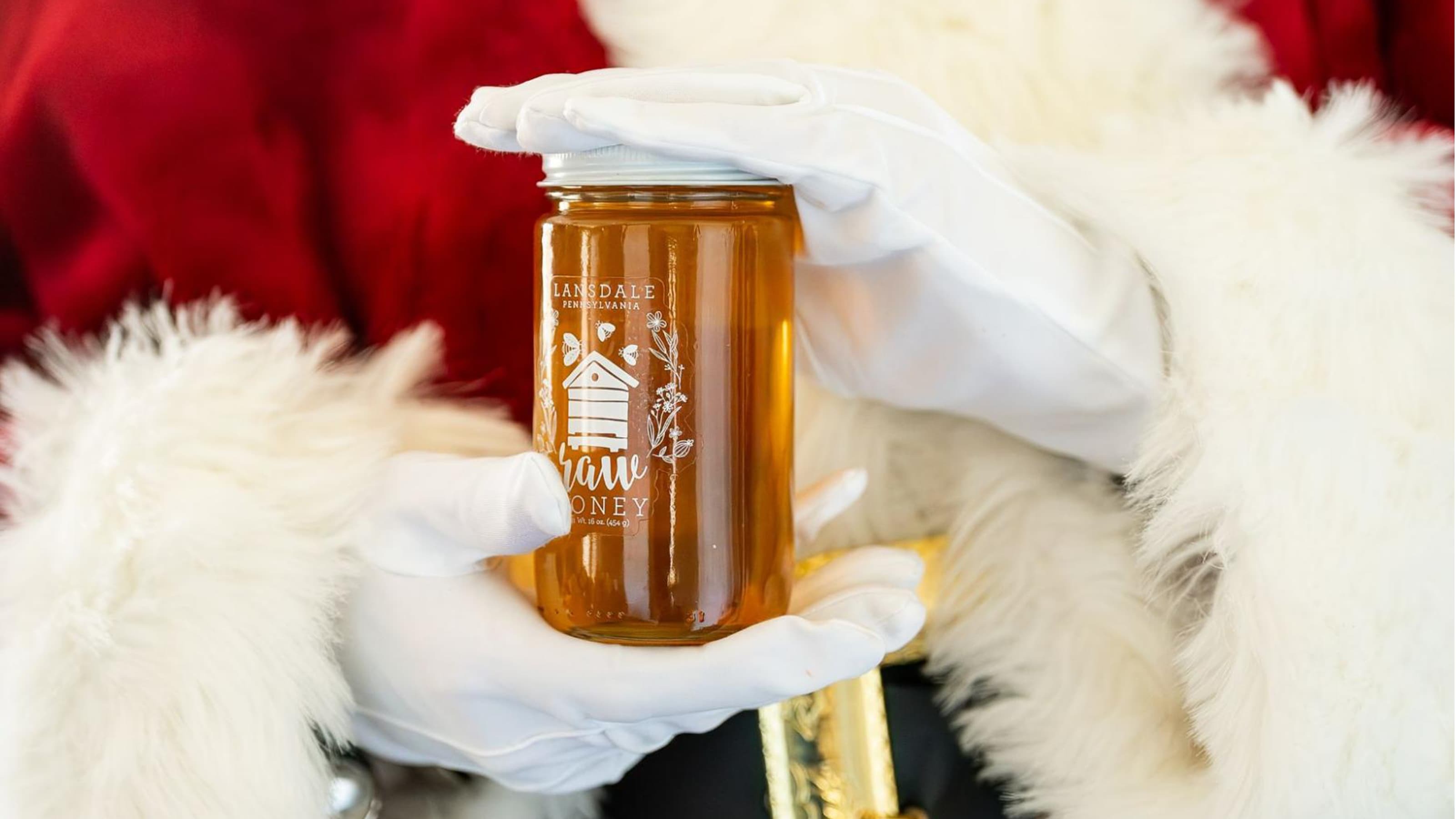 Santa's hands holding a jar of honey.