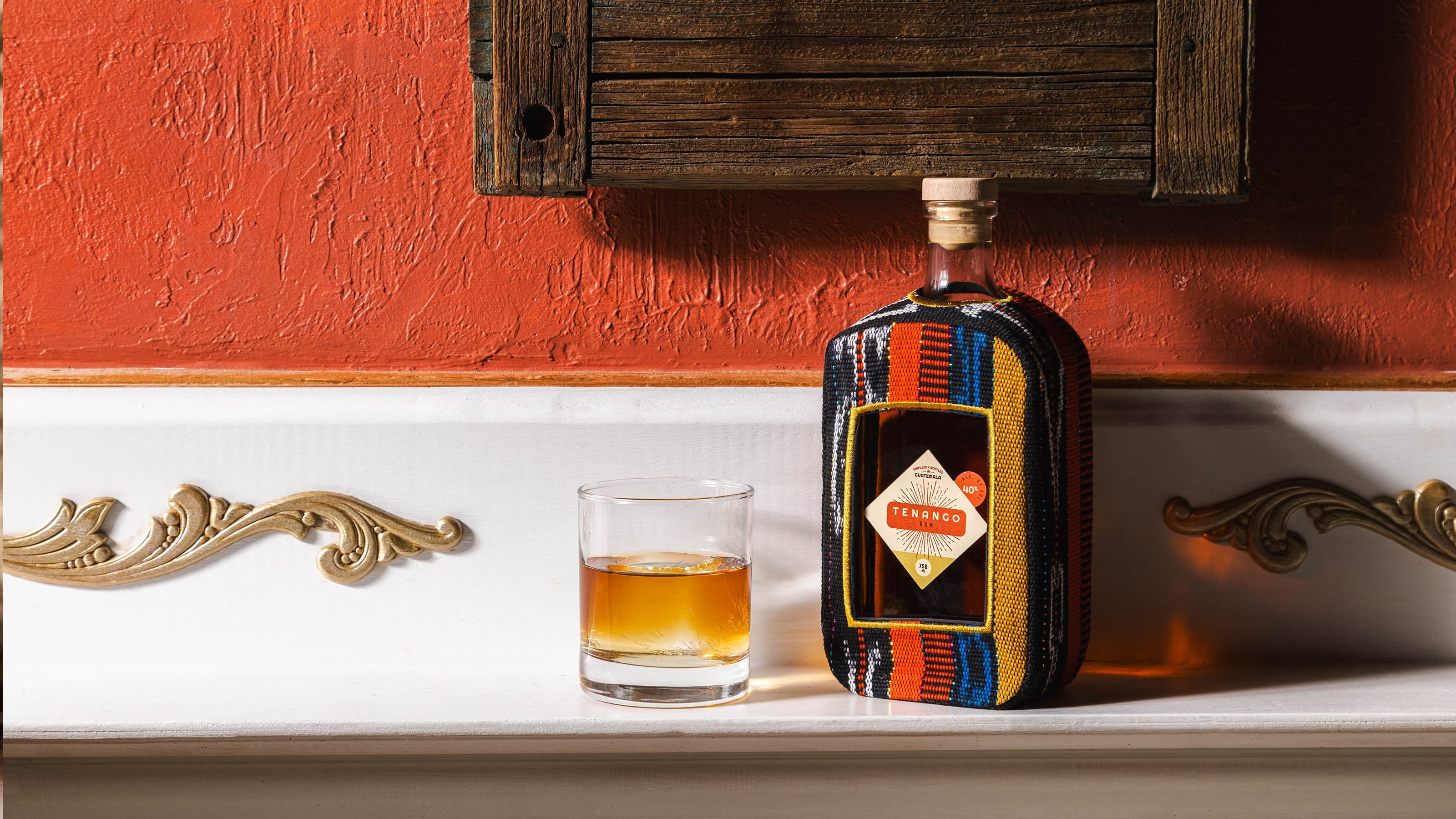 Bottle of Tenango rum sitting on a white shelf with an orange painted wall in the background.