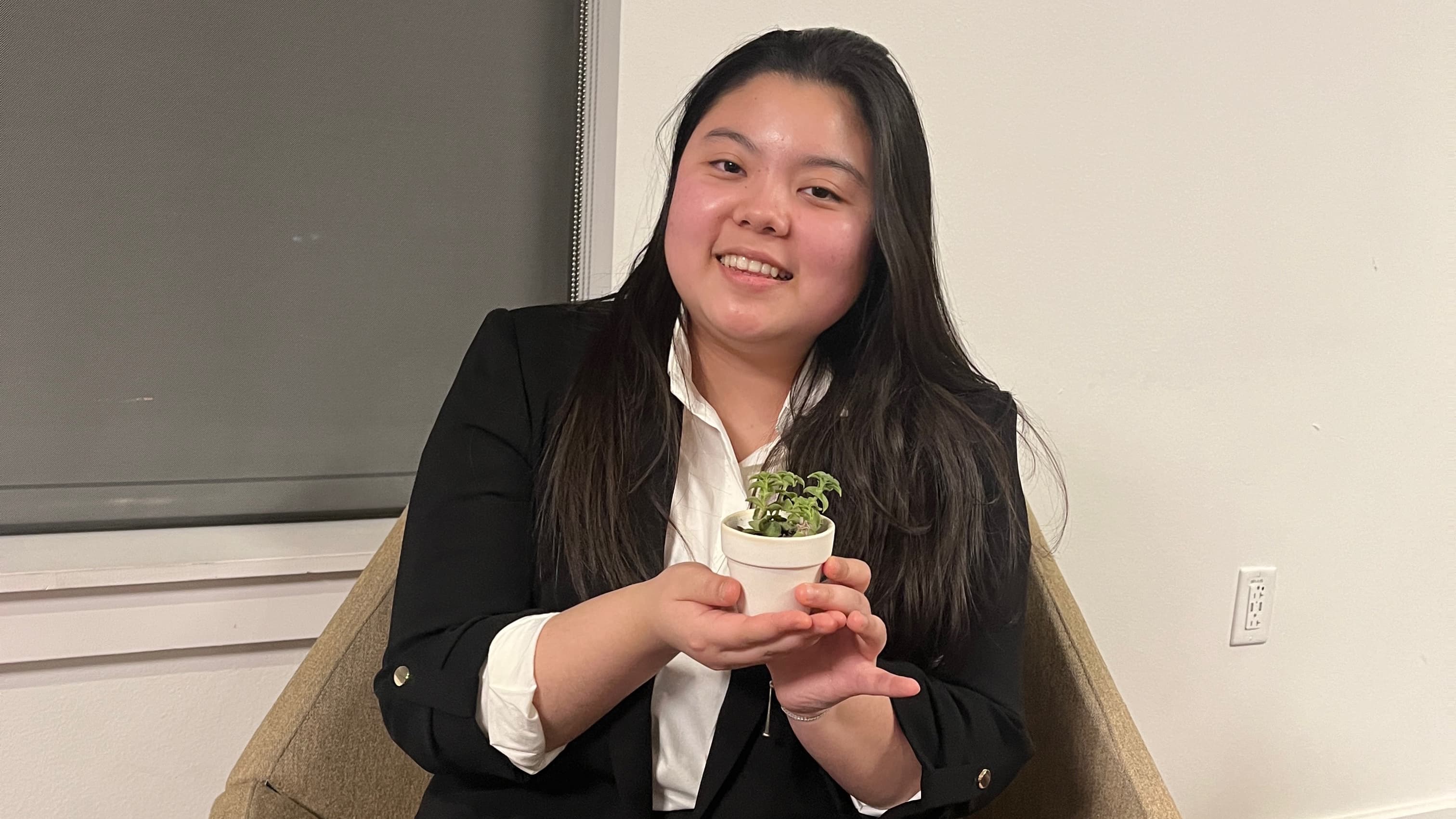 Female wearing suit and holding a small plant
