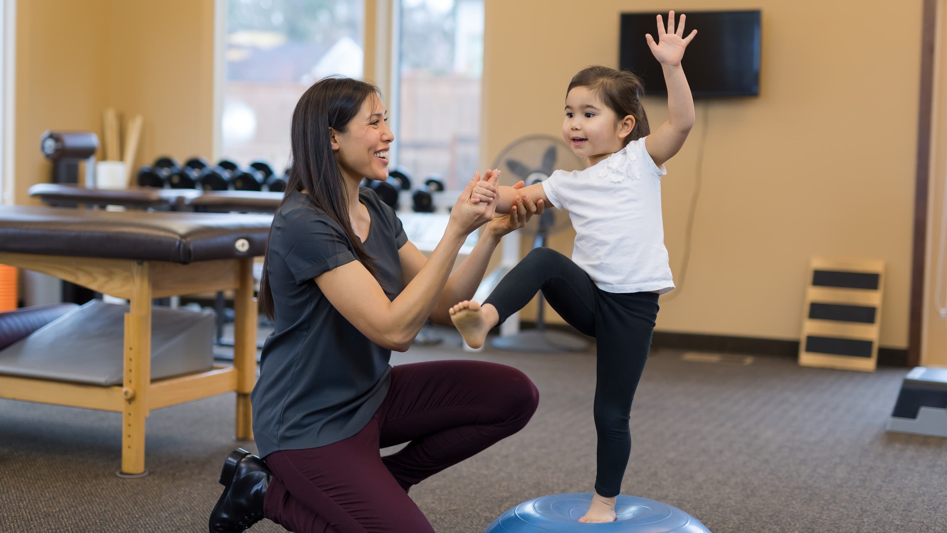 Physical therapist working with child to help her exercise