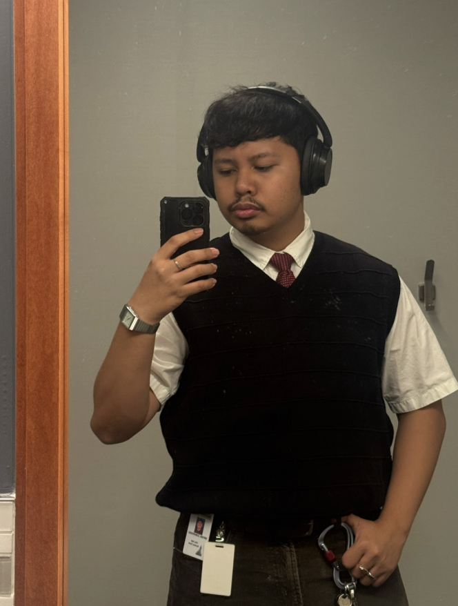 Bryan Jumarang taking a selfie in the mirror wearing a white top and burgundy vest