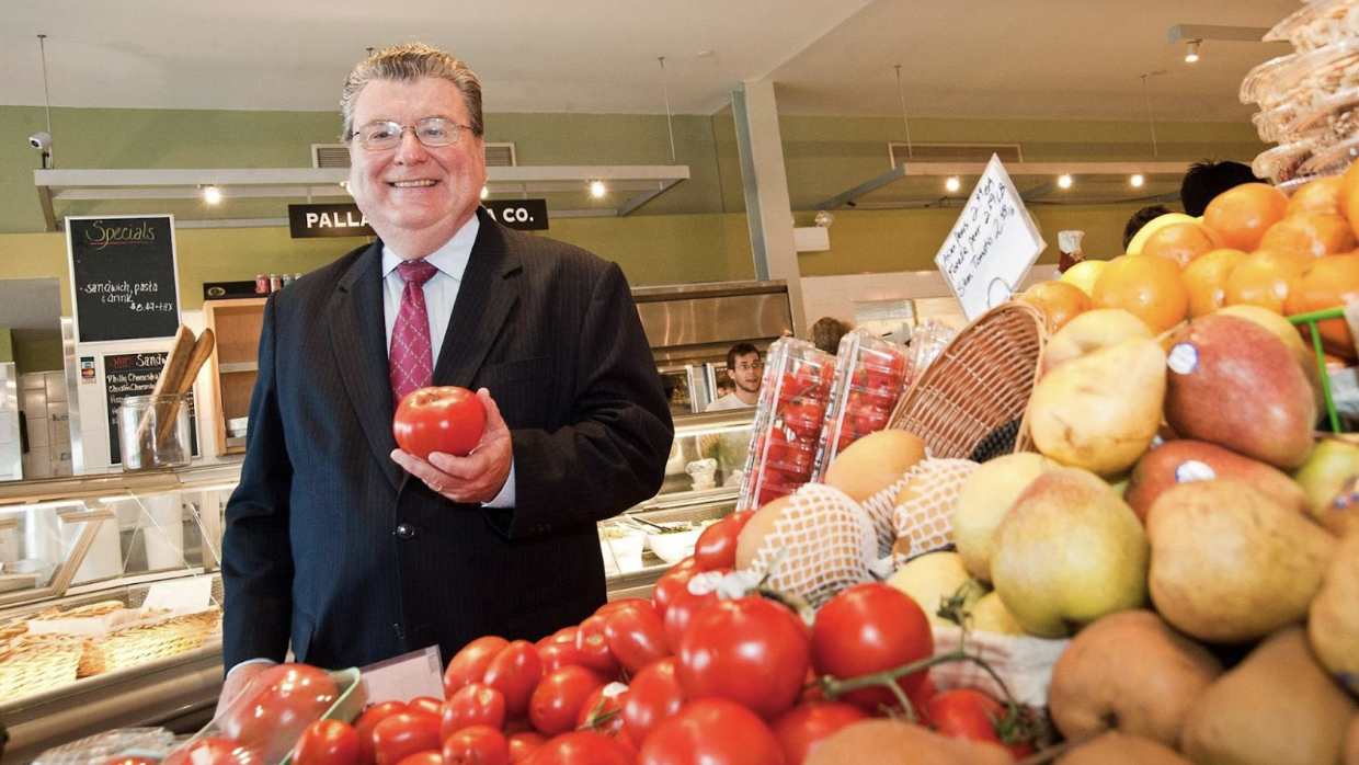 John Stanton in a grocery store holding a tomato