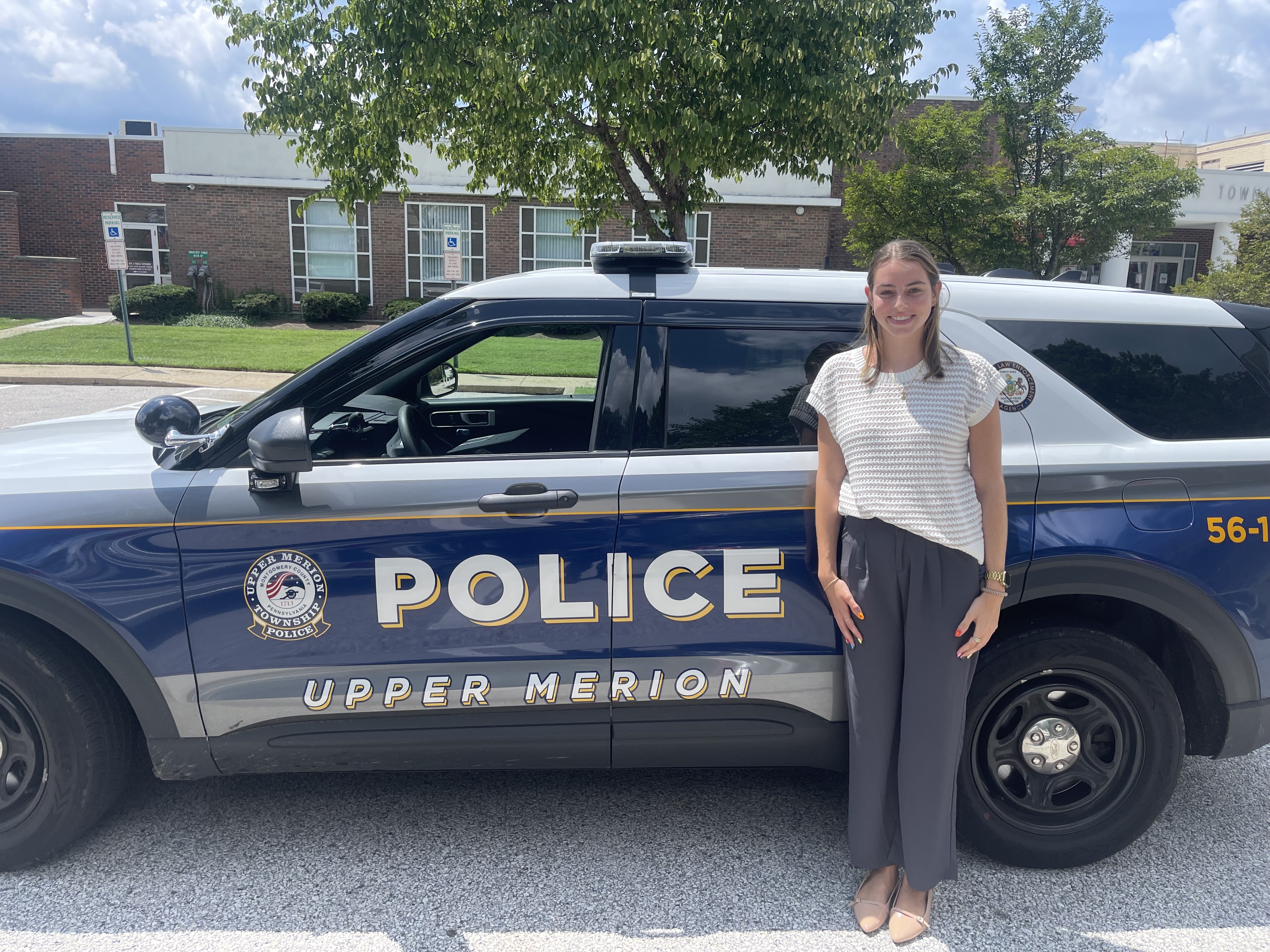 Ava smiling in front of a Upper Merior township police vehicle