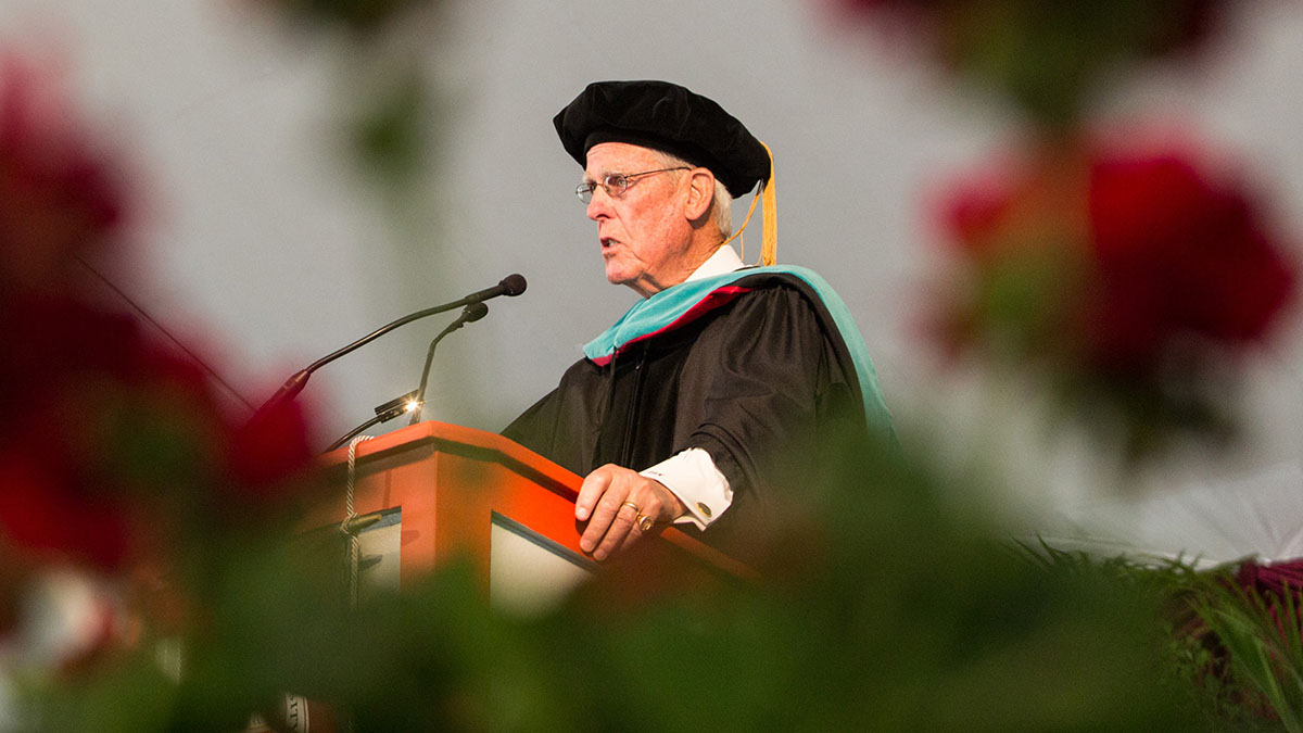James Maguire dressed in regalia standing at a podium
