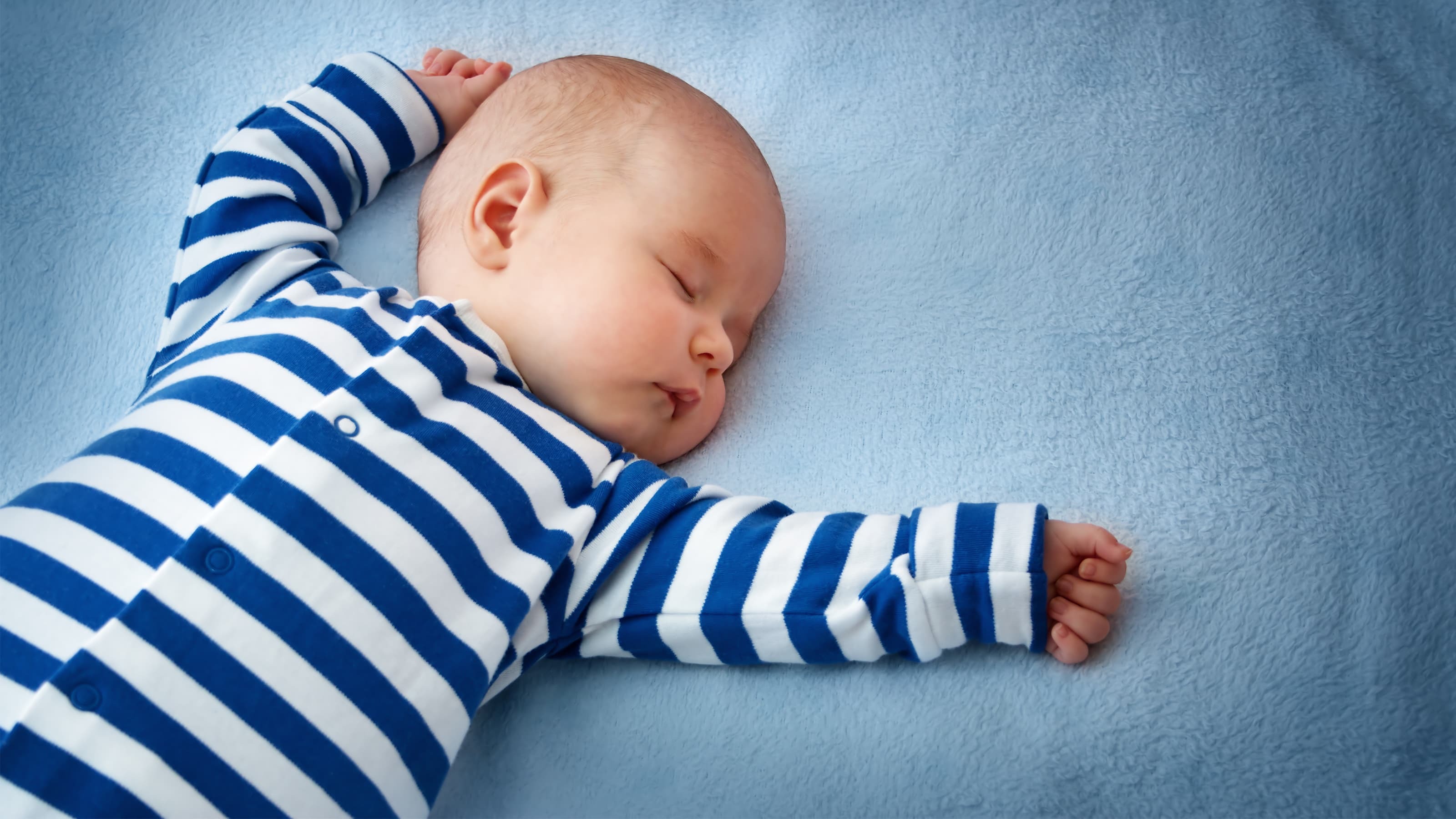 A baby asleep on a blue sheet