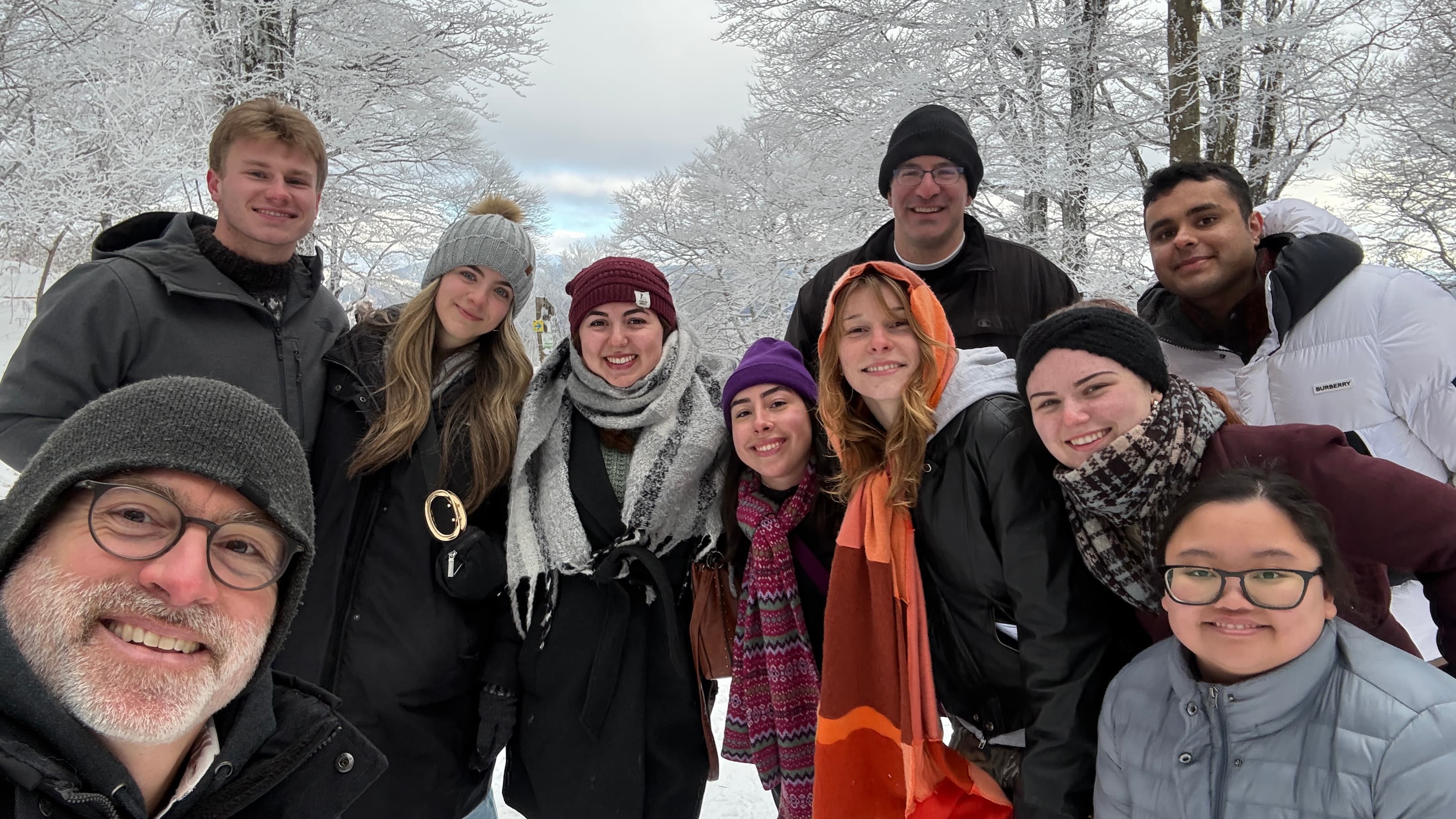 A group of students and professors in front of snow-covered trees