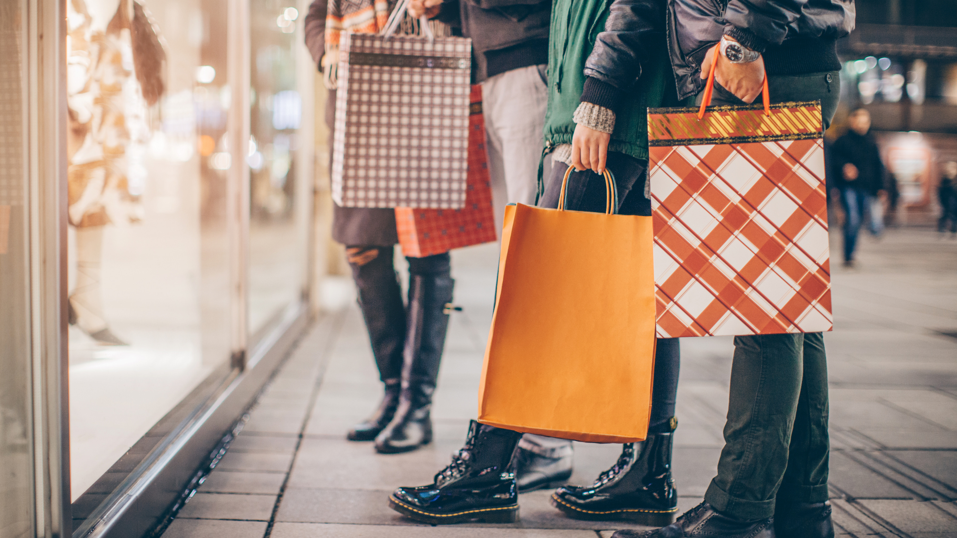 People window shopping while holding holiday bags in their hands. 