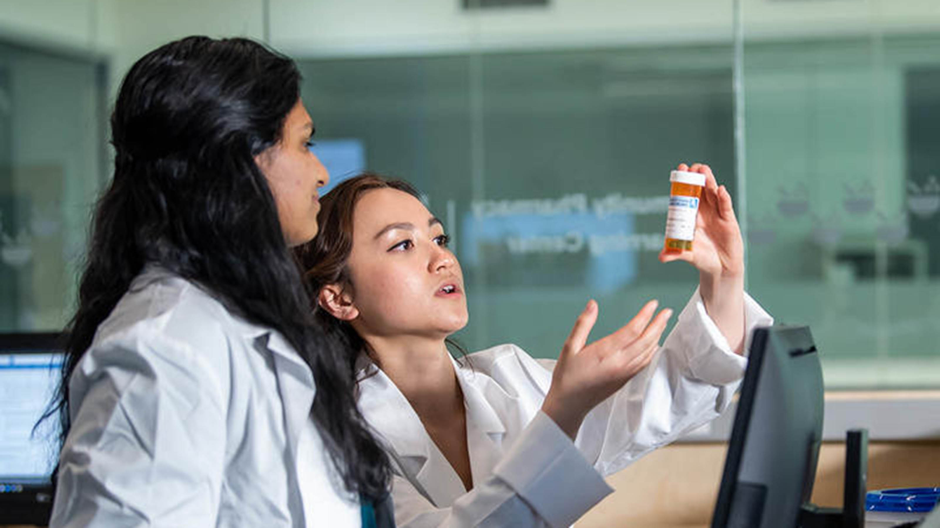 Two female Saint Joseph's PCP students looking at medicine bottle