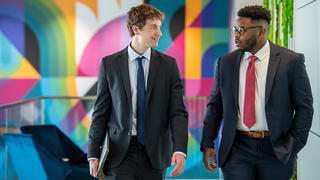 Two male business men walking and talking together