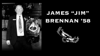 Jim Brennan in a suit holding the Hawk mascot head, next to which it reads "James 'Jim' Brennan '58" in white text against a black background with a hawk logo below