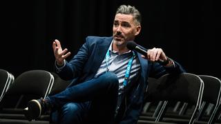 Brendan Quinn leaned back in a folding chair holding a microphone