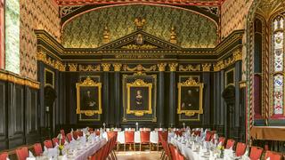 Ornate black and gold room with white tables and red chairs