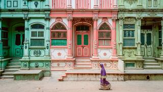 Woman walking in front of colorful buildings