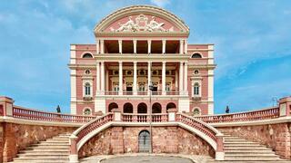 Pink and white building with columns and large staircase against blue sky
