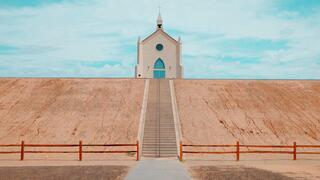 Stairs leading up to a white church on a dusty, flat hill