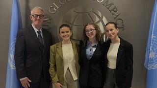 A professor and three students standing in front of the United Nations logo