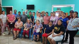 A group of Salvadoran adults looks at the camera in front of a bright blue wall